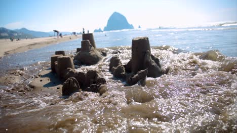 Waves-crashing-over-sandcastle-on-the-beach