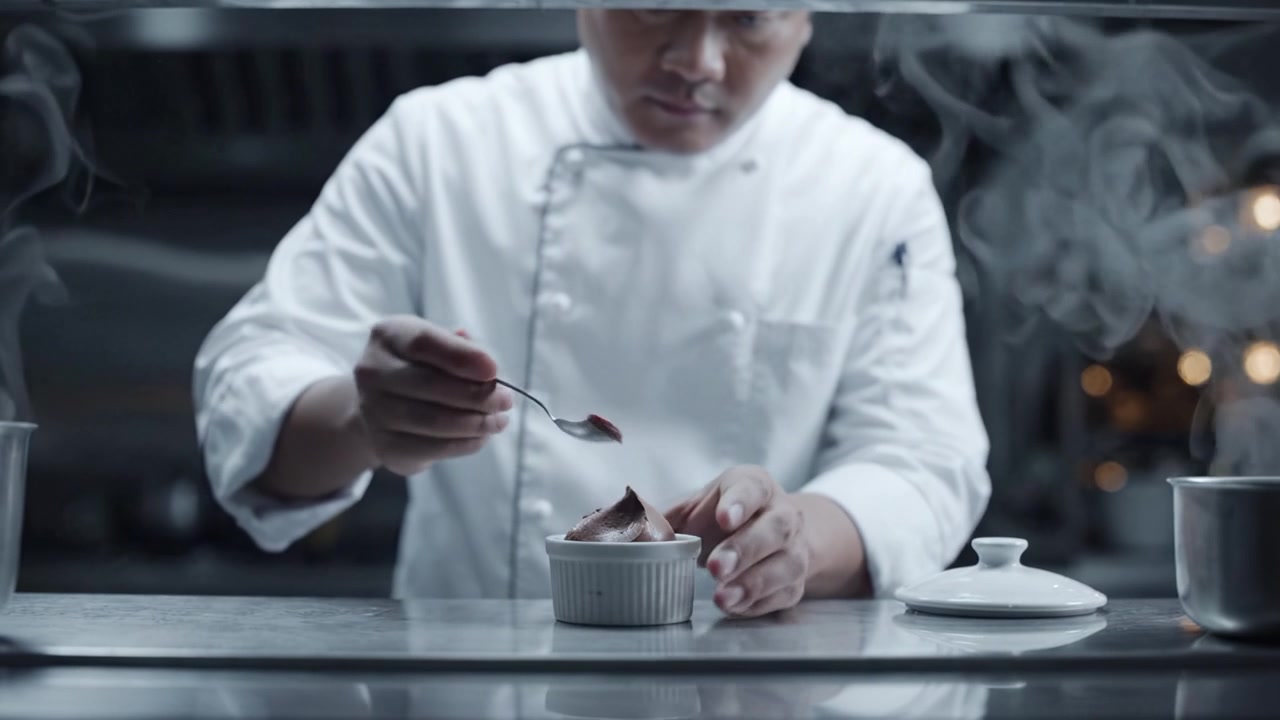 Uno chef prepara meticolosamente un dessert gourmet con un tocco delicato, mettendo in mostra una presentazione artistica in un ambiente di cucina sofisticato.