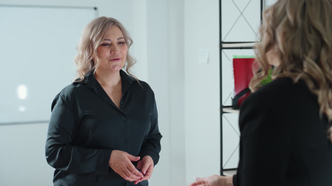 real estate agent rises to present key as client stretches forth hand to receive key and they exchange handshake with warm demeanor beside pen holder on office table