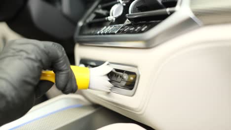 a employee of a car wash washes the car inside he wipes the instrument panel with a special brush. a young employee of a car wash washes the car inside, he wipes the instrument panel with a special brush