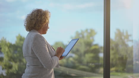 mujer usando la tableta junto a la ventana