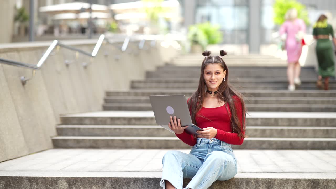 una mujer joven con una computadora portátil sentada en las escaleras
