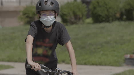 medium portrait of a kid on a bike wearing a medical mask and looking into camera