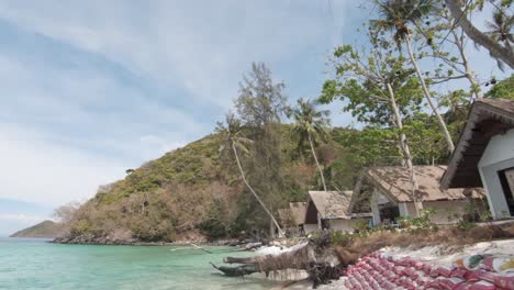 Sandbag-barrier-protected-shoreline-with-tourism-resort-shacks-in-Koh-Hey-,-Thailand---Wide-push-in-gimbal-shot