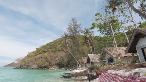 sandbag barrier protected shoreline with tourism resort shacks in koh hey , thailand - wide push in gimbal shot