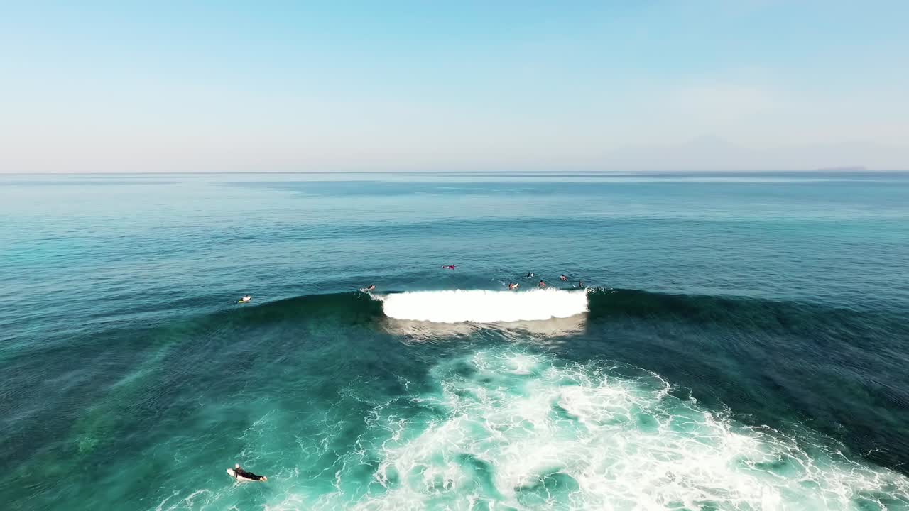 Aerial drone view of a group of surfers and large waves, at Jelenga beach, in Sumbawa