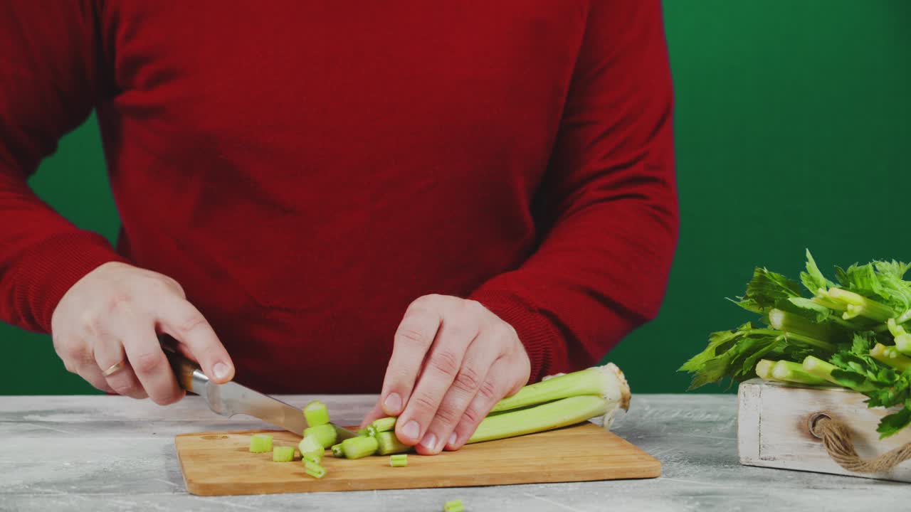 человек режет сельдерей на доске для резки.
