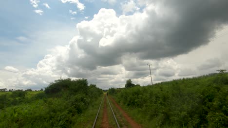 un punto de vista en cámara lenta tomado de un tren que se mueve lentamente a lo largo de una vía férrea en áfrica rural mirando hacia las nubes