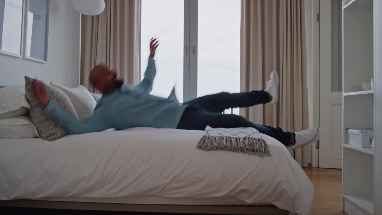 hombre cansado saltando en la cama descansando después de un viaje disfrutando relajándose en casa