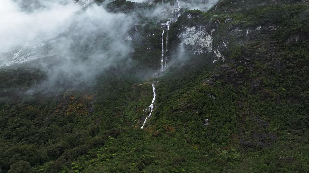 dolly aéreo a cascada de varios niveles con nubes bajas en milford sound
