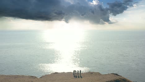 the four people standing on the mountain top on the seascape background