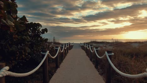 cinematic-POV-video-walking-towards-the-beach-on-a-cloudy-and-sunny-evening-in-america