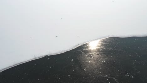 Top-View-Of-Winter-Snow-Landscape-In-Birds-Island,-Poland-During-Sunrise-With-Reflection-In-Water---Aerial-Drone-Shot