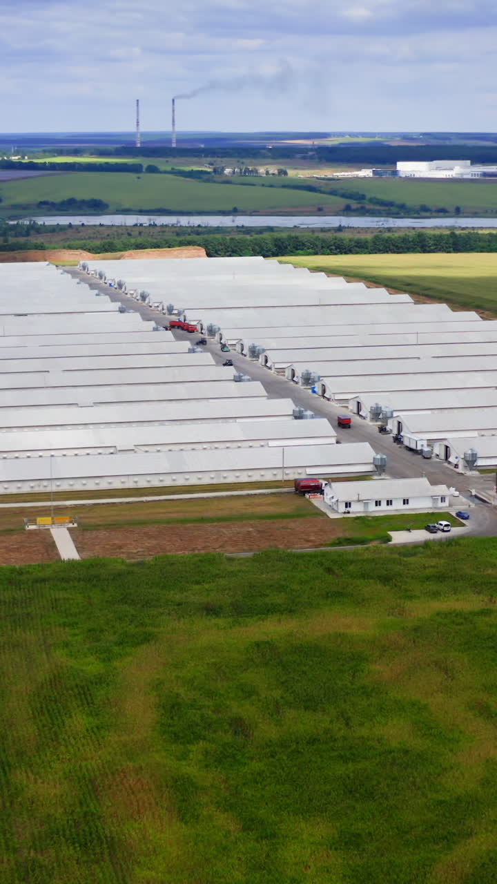 Innovative farm on field in the countryside. Large agricultural area on beautiful green landscape. Harmful factory among nature. Aerial view. Vertical video