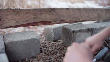 the man is compacting the gravel underneath and then using a level to align the diy hot tub - close up