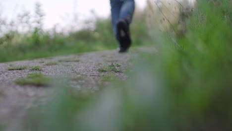 Young-man-walking-in-park,-close-up-shot-sneakers,-slow-motion,-blurry-background