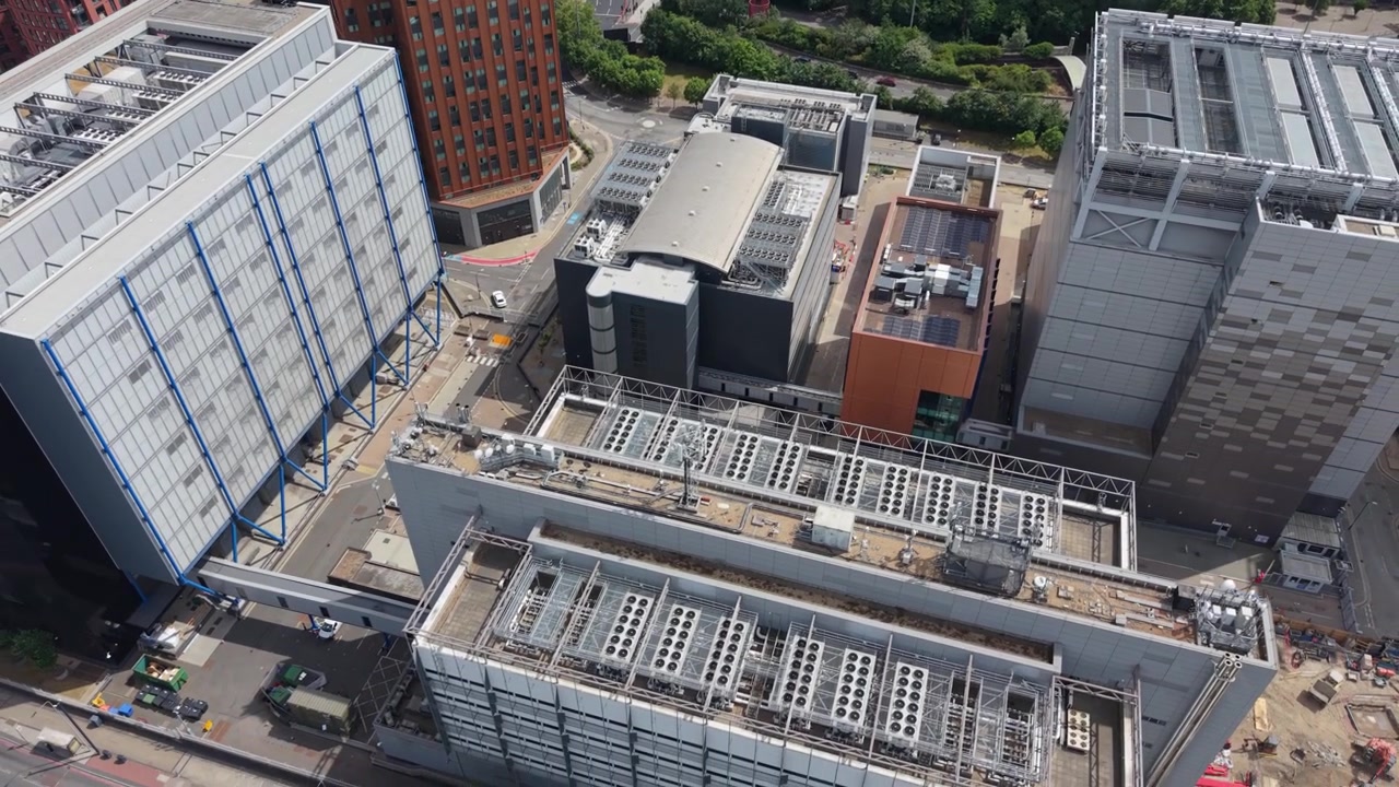 Aerial perspective of a large Data Centre complex during daytime. Observe modern buildings with extensive rooftop cooling systems and infrastructure.