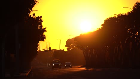 Wunderschöner-Sonnenuntergang,-Während-Autos-Die-Stadtstraße-Entlangfahren