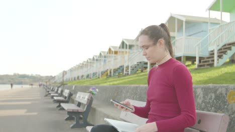 Eine-Junge-Frau-Schaltet-Ihr-Telefon-Aus-Und-öffnet-Ihren-Laptop,-Um-Sich-Am-Strand-Zu-Entspannen-Und-Zu-Arbeiten