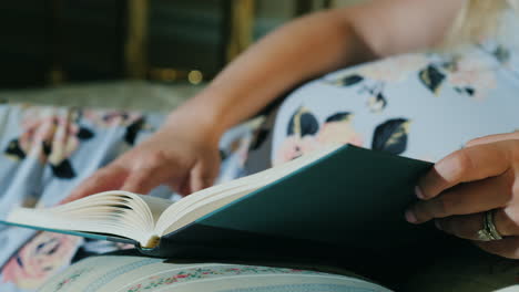 pregnant woman reads a book in her bed close-up shot