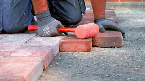 paving worker lay stone pavers in rows and tap gently with paving mallet