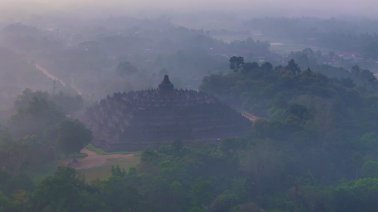 Misterius scene of huge temple surrounded by trees shrouded by mist