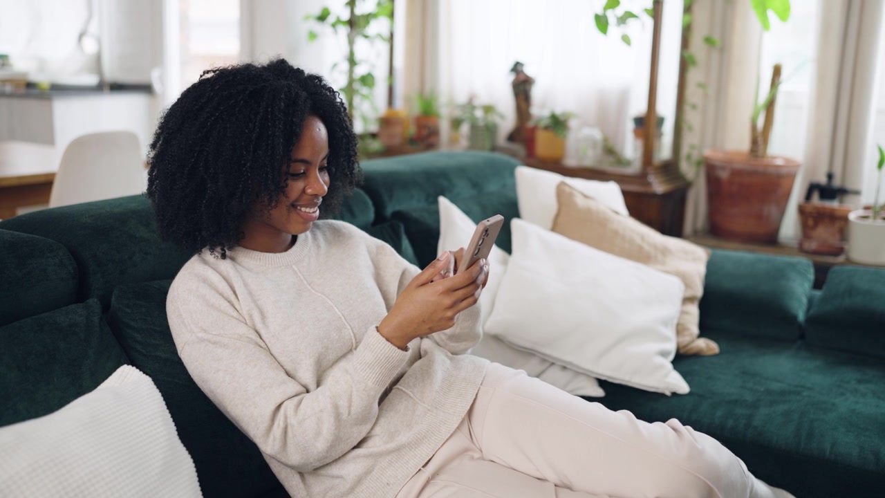 Happy African American Woman Relaxing on Couch and Using Smartphone