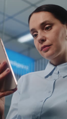 mujer que utiliza un teléfono inteligente en un entorno de oficina
