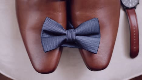 cerca de zapatos de cuero marrón pulido con una corbata azul elegantemente colocada entre ellos