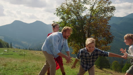 familia alegre se divierten en las montañas. padres jugando con los niños en la naturaleza