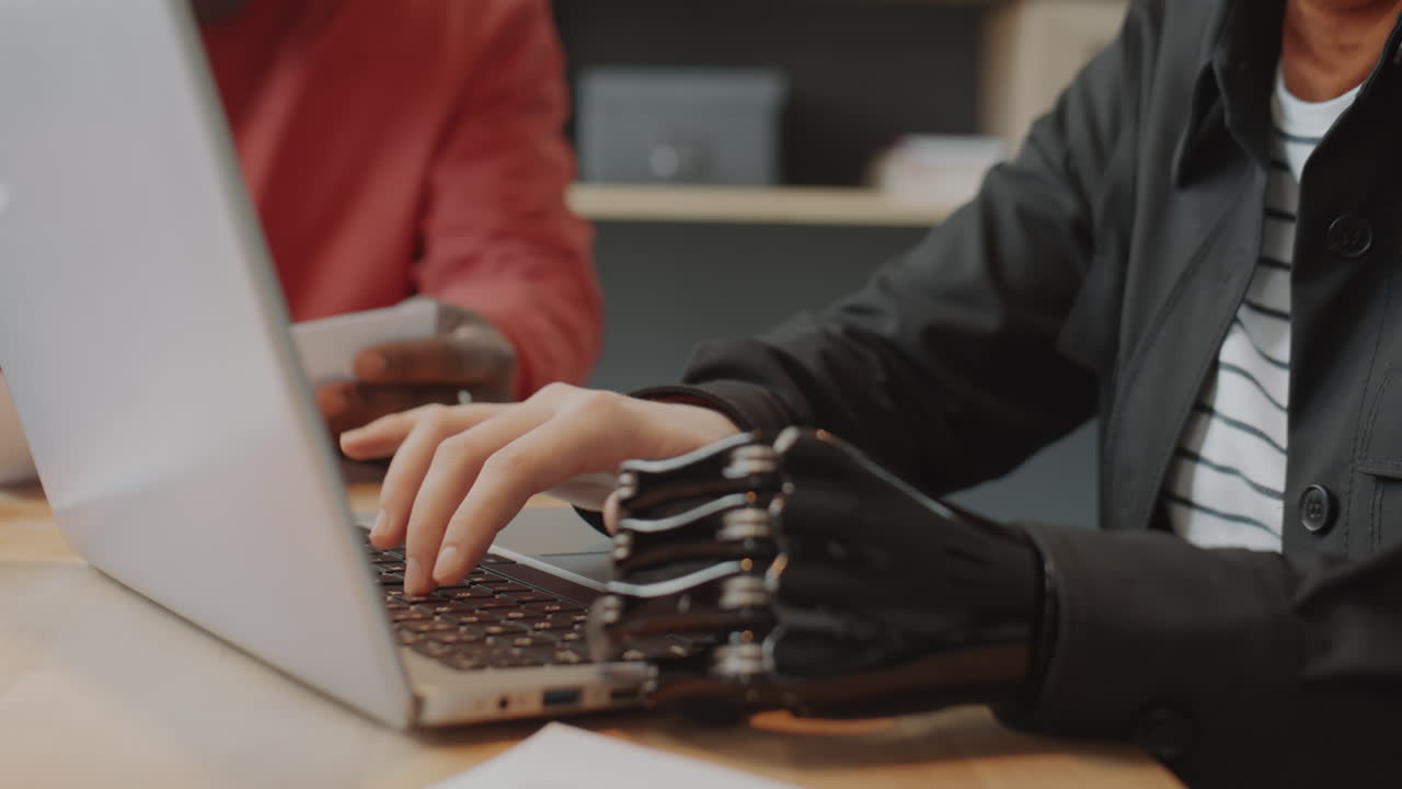 Woman with Prosthetic Arm Working on Laptop during Office Meeting