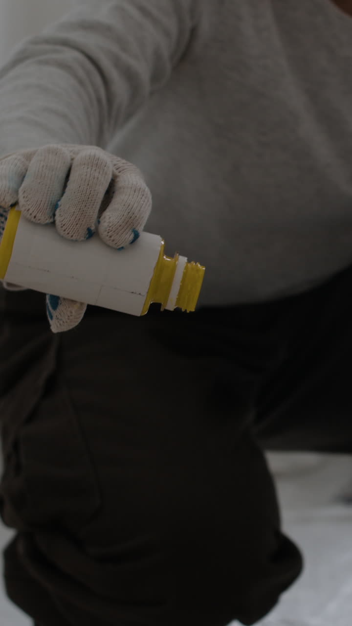 Close-up of a Person Pouring Yellow Paint from a Bottle