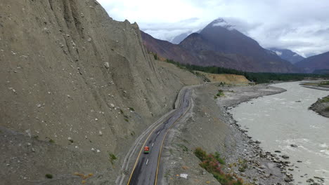 cinematic drone shot following a tuk-tuk on the karakoram highway pakistan along the hunza river