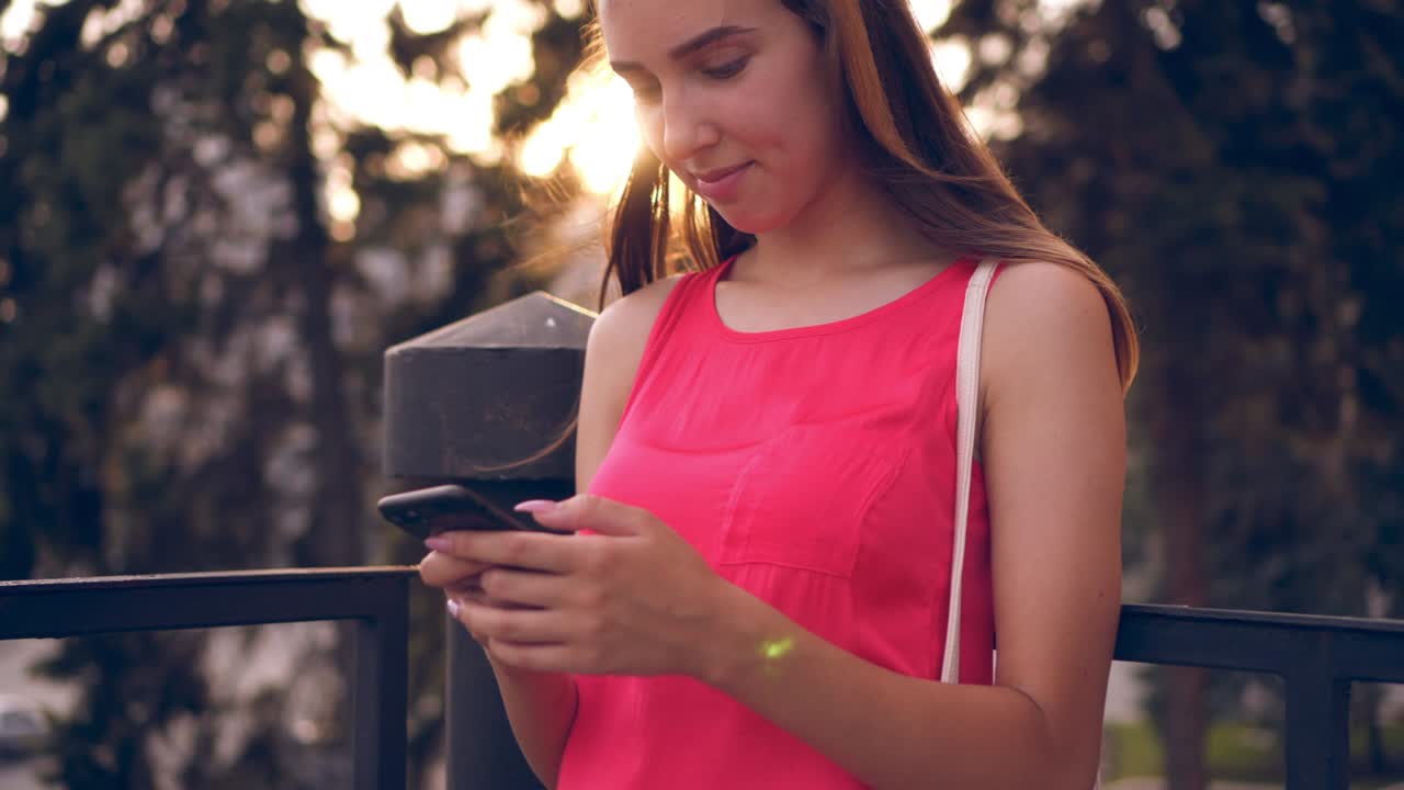 una joven hermosa enviando mensajes de texto con sus amigos en su teléfono inteligente.