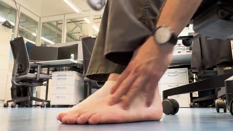 el hombre se quita los calcetines y masajea los pies.