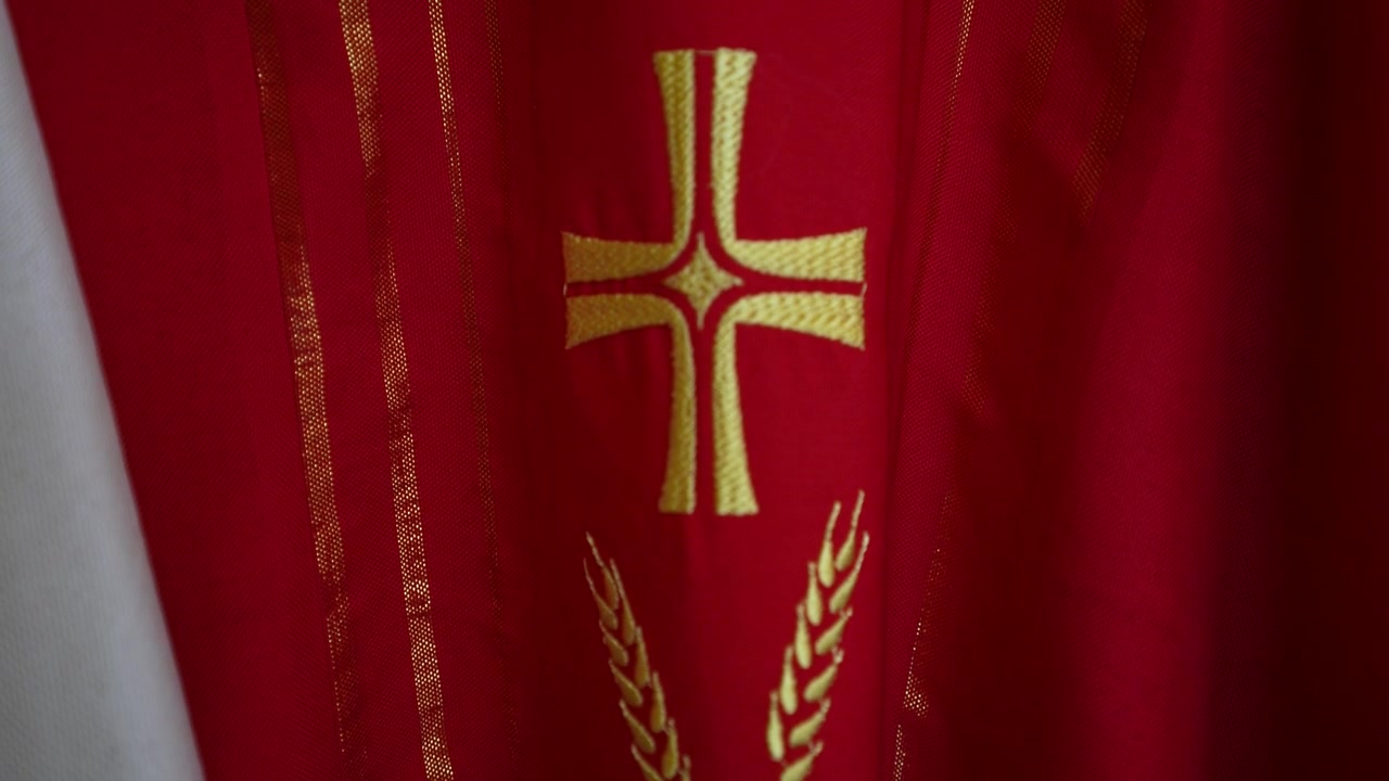 Casula sacerdotal vermelha com bordado detalhado de cruz dourada para cerimônias religiosas.