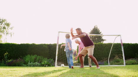 Tres-Generaciones-Masculinas-De-Una-Familia-Jugando-Al-Fútbol-En-El-Jardín