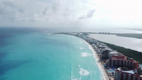 coast with emelard color water beach. sand, waves, trees, road and buildings in caribbean sea coast on the yucatán peninsula. some clouds. wide aerial shot.