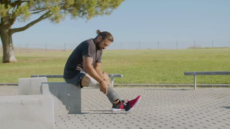 athletic man putting on artificial leg before working out.