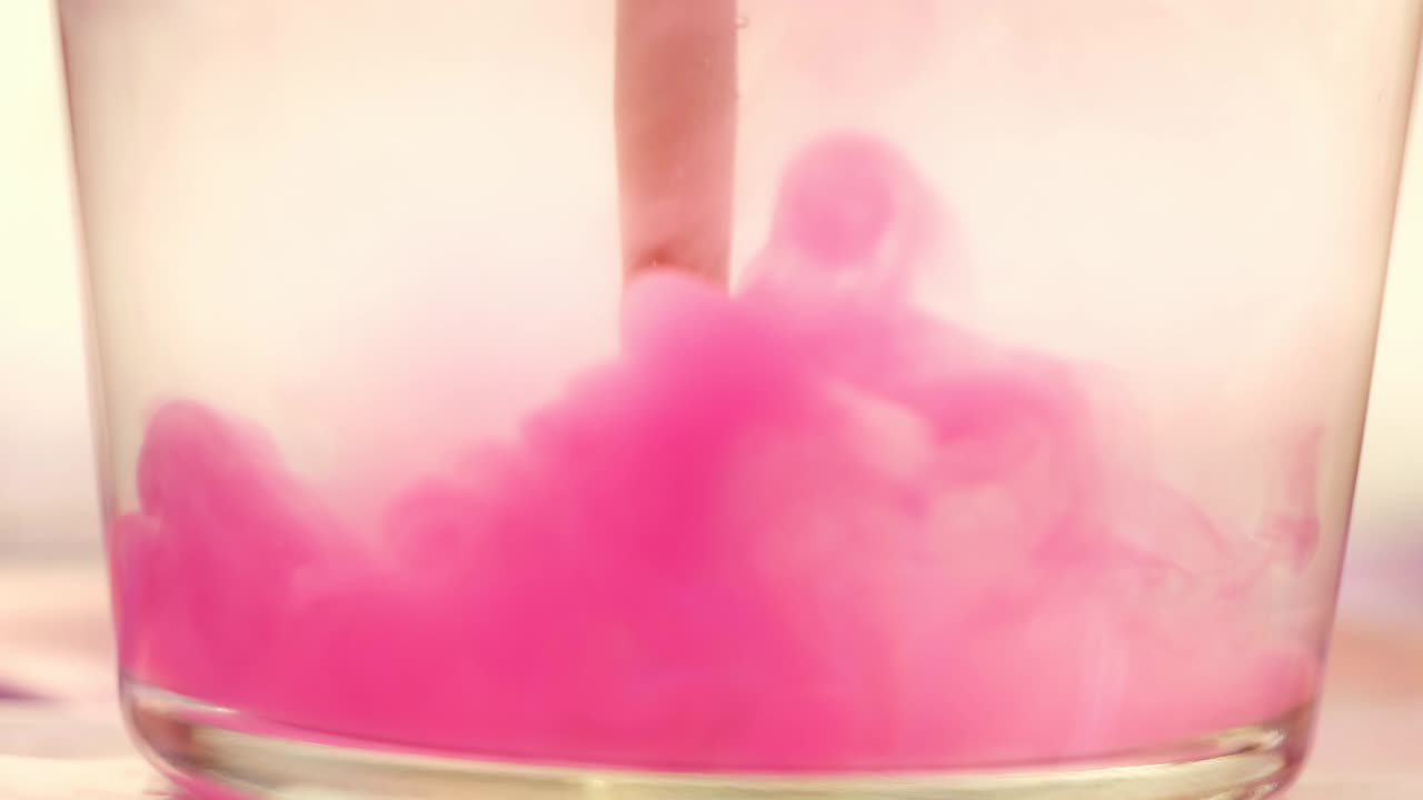 cerrar el pincel de pintura rosada en el vaso de agua. concepto. poner un pincel con pintura rosa en el agua transparente con hermosas nubes de pintura