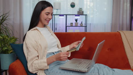 mujer joven usando tarjeta de crédito y computadora portátil, transfiriendo dinero, comprando compras en línea