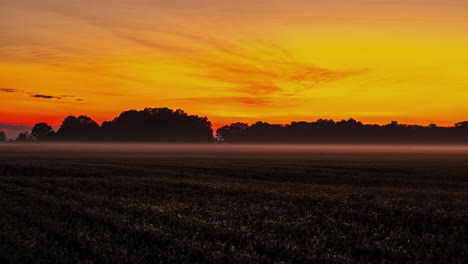 A-golden-sunset-with-low-lying-fog-over-the-farmland-fields---time-lapse