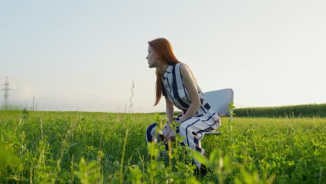 woman in striped dress sitting in a field at sunset
