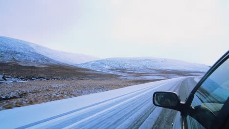 vista de majestuosas montañas cubiertas de nieve y carretera desde la ventana lateral del coche en marcha