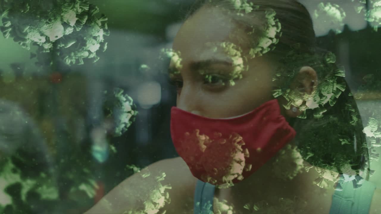 Woman wearing red mask in gym listening offscreen and turning as virus overlay sweeping across face