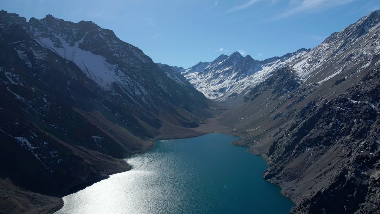 Veduta aerea in picchiata della Laguna del Inca, nelle Ande cilene, al confine tra Cile e Argentina, con montagne innevate sullo sfondo