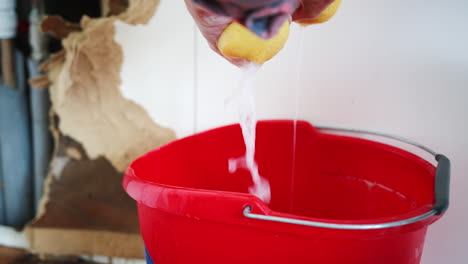 close up as woman squeezes water into bucket after domestic leak