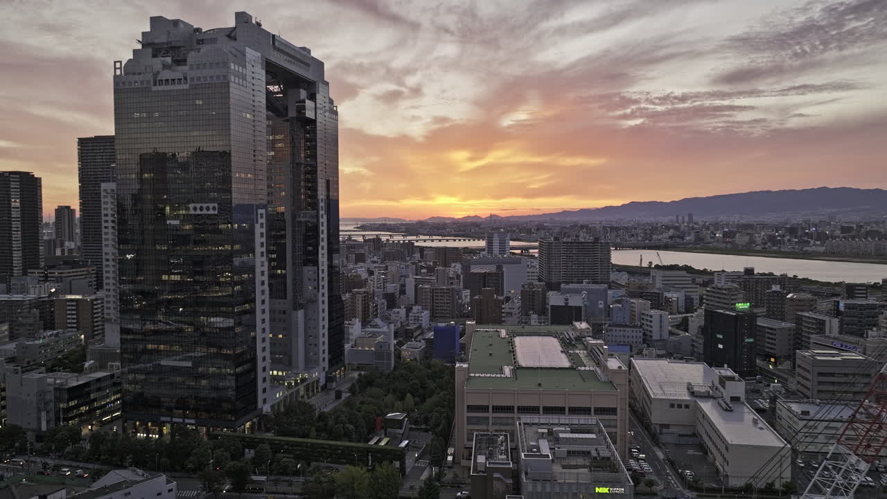 Osaka, Japão. Sobrevoo reverso aéreo de drone baixo v84 entre edifícios em Ofukacho, capturando a paisagem urbana do centro de Oyodonaka, Distrito de Kita, e o rio Yodo ao pôr do sol. Filmado com Mavic 3 Pro Cine - 9 de outubro de 2023.
