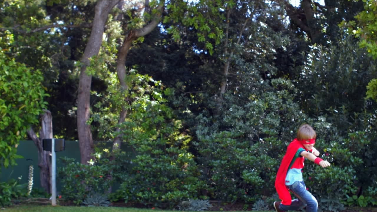 정원에서 슈퍼 히어로를 연기하는 귀여운 소년