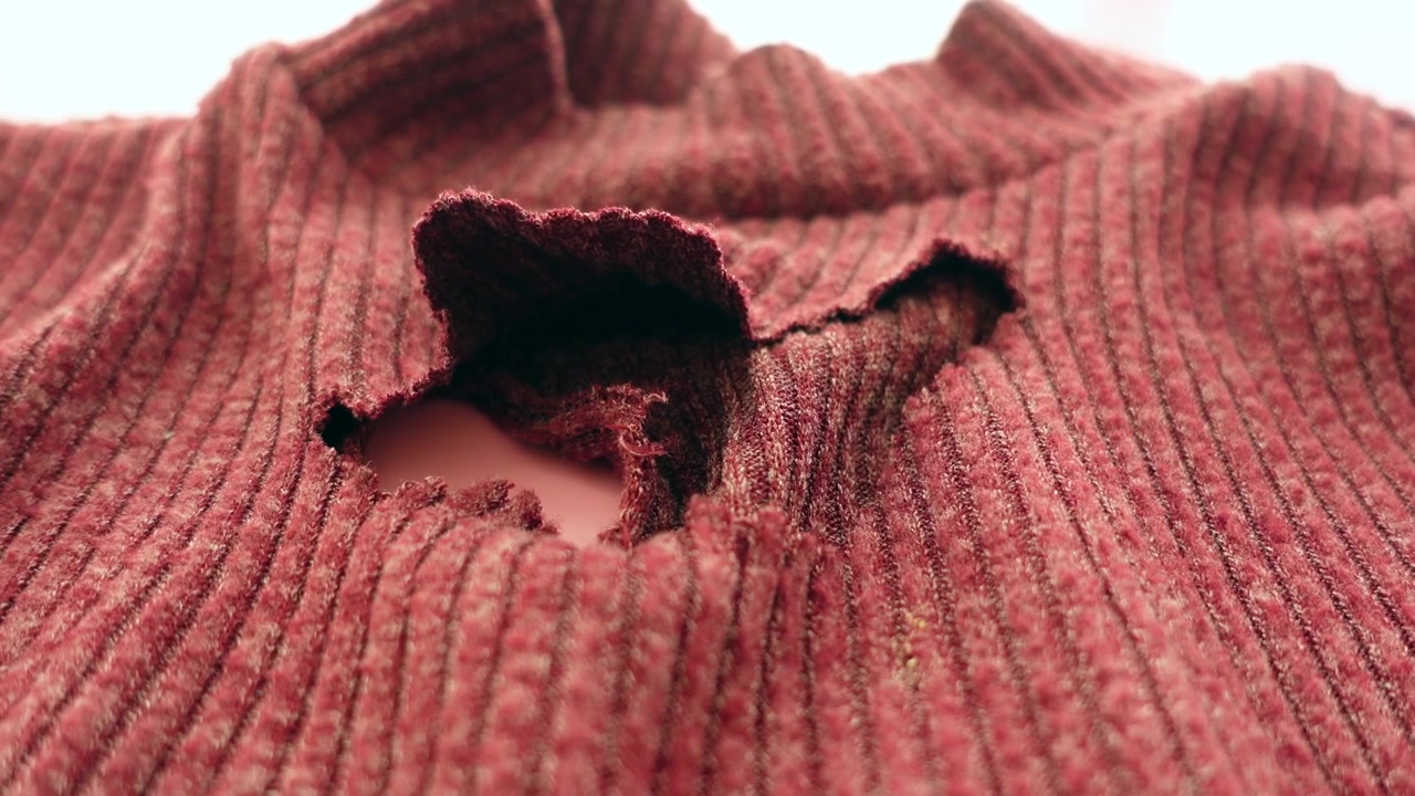 Primo piano di un buco in un tessuto a coste rosso
